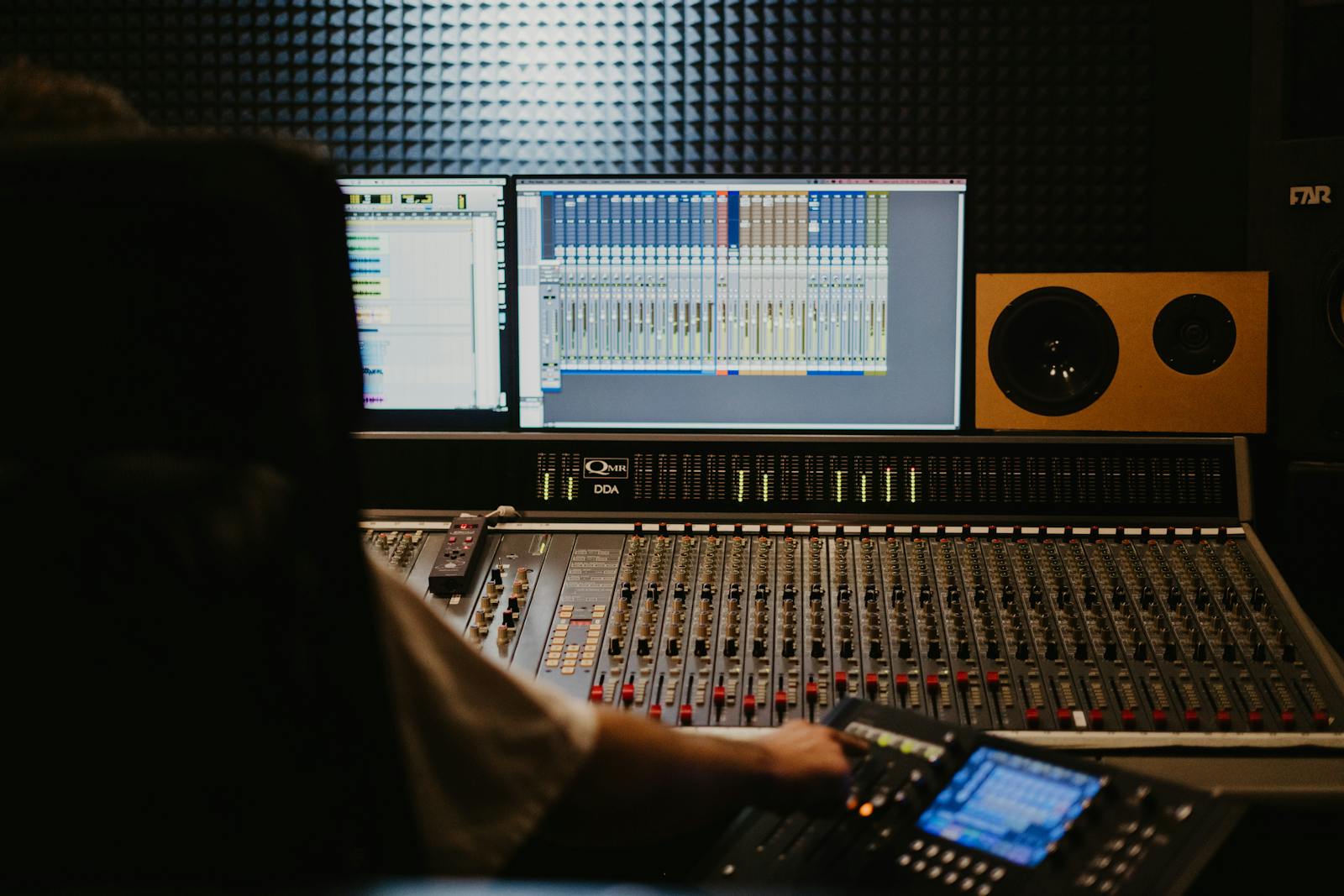 An audio console covered in level faders and knobs, the kind of metering surface where the sound stage of a quality-control process is measured against fixed loudness targets.