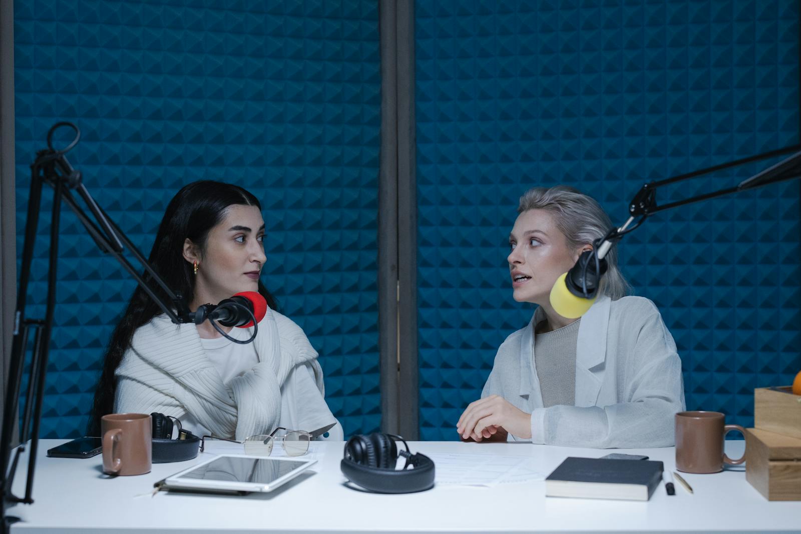 Two people recording a podcast with microphones in a soft-lit room, the kind of talking-to-camera content where TikTok loudness and the voice-to-music balance decide whether the audio feels right.